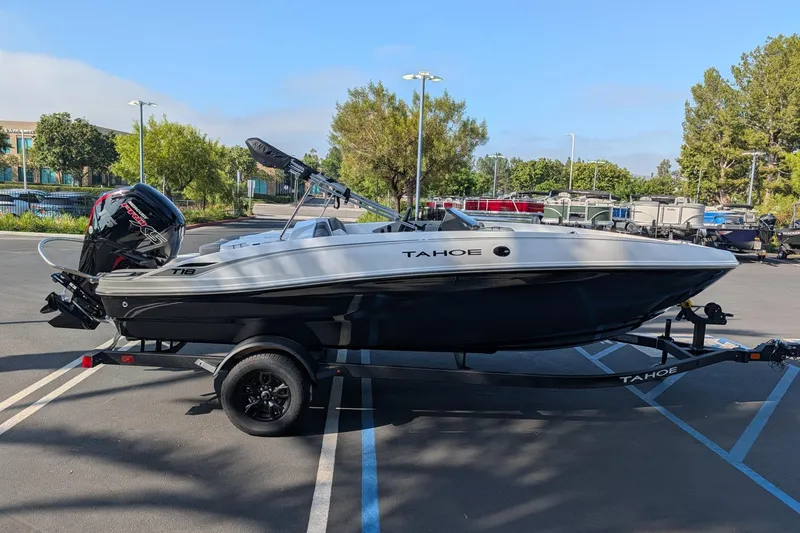 Slide: The Image of 2027 Tahoe T18 boat on trailer in parking lot, surrounded by trees and other boats. - 6