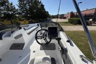 Slide: The Image of 2027 Tahoe T21 boat interior with steering wheel and control panel, parked outdoors. - 2