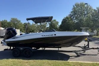 The Image of 2027 Tahoe T21 boat on trailer, parked outdoors, with canopy and sleek design. - 0