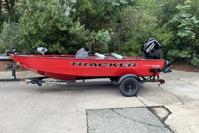 The Image of Red 2027 Tracker Super Guide V-16 SC boat on trailer, parked outdoors. - 0