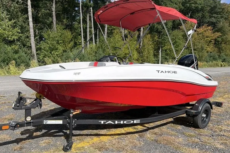 Slide: The Image of Red and white 2027 Tahoe T16 boat with canopy on trailer, parked outdoors. - 0