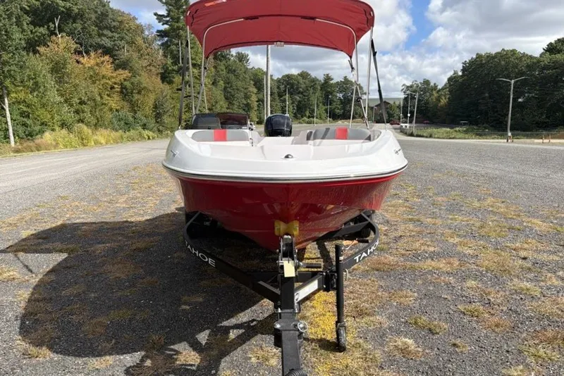 Slide: The Image of Red 2027 Tahoe T16 boat on trailer, parked outdoors with trees in background. - 5