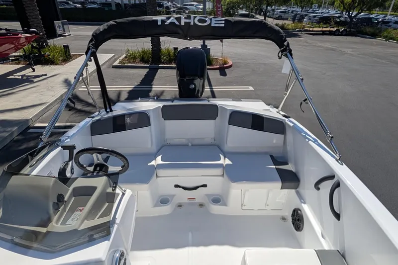 Slide: The Image of 2027 Tahoe T16 boat interior with seating and steering wheel, parked outdoors. - 9