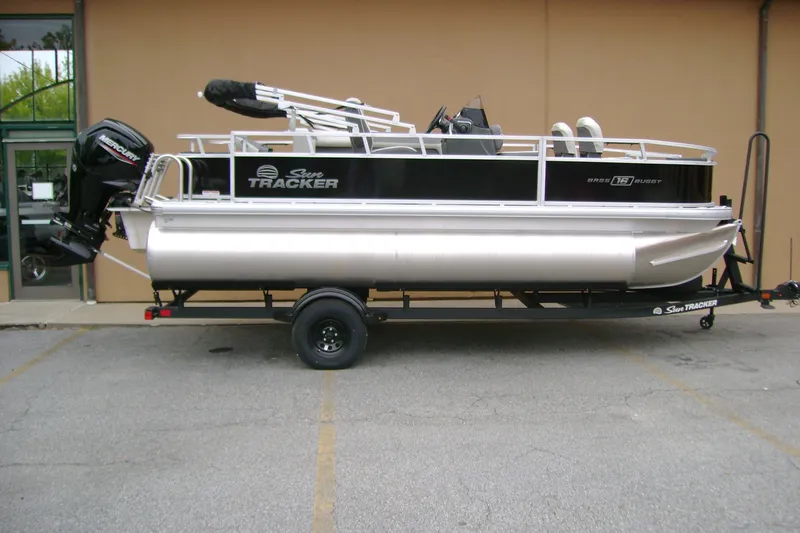 The Image of 2027 Sun Tracker Bass Buggy 18 DLX pontoon boat on trailer, parked outdoors. - 0