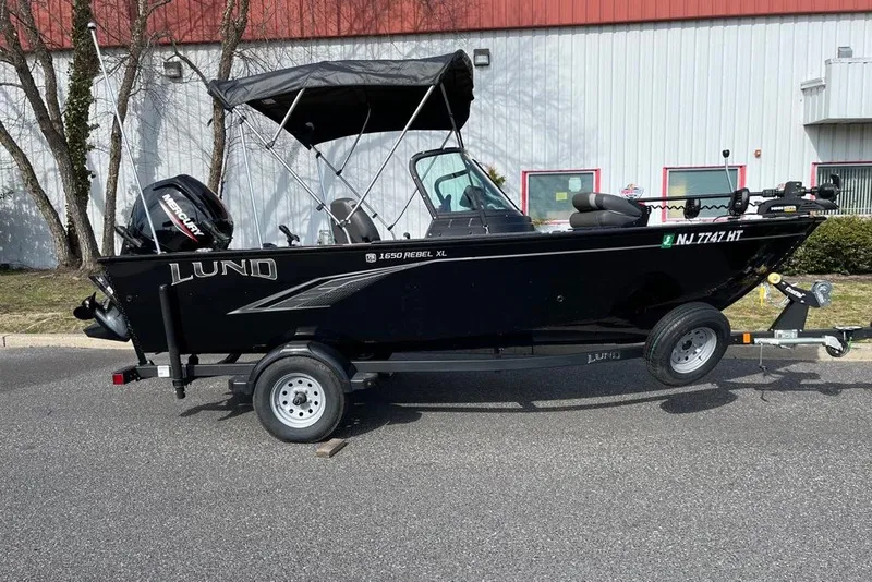 Slide: The Image of 2023 Lund 1650 Rebel XL Sport boat on trailer, parked outdoors. - 0