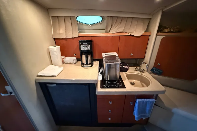 Slide: The Image of Compact kitchen area in a 1998 Wellcraft 3200 Martinique boat, featuring a sink and appliances. - 42