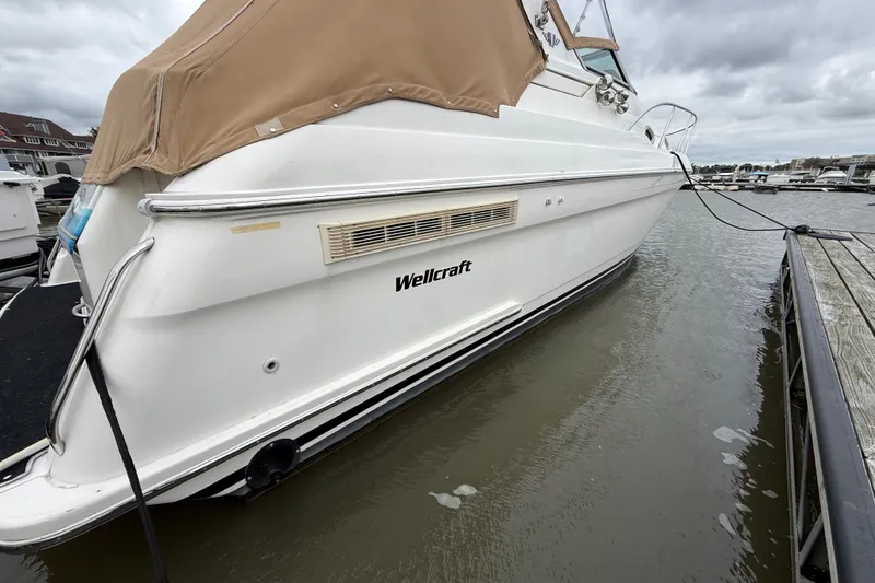 Slide: The Image of 1998 Wellcraft 3200 Martinique boat docked at marina, featuring tan cover and sleek design. - 3