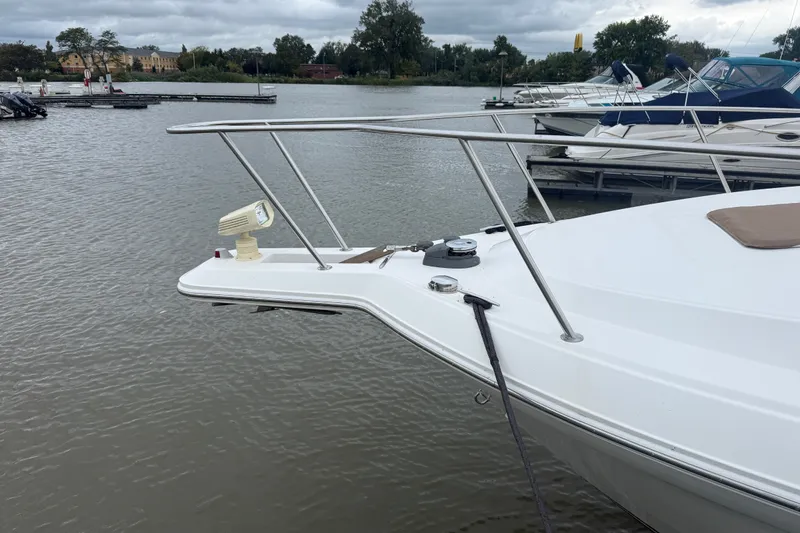 Slide: The Image of 1998 Wellcraft 3200 Martinique boat docked on a calm lake under cloudy skies. - 9