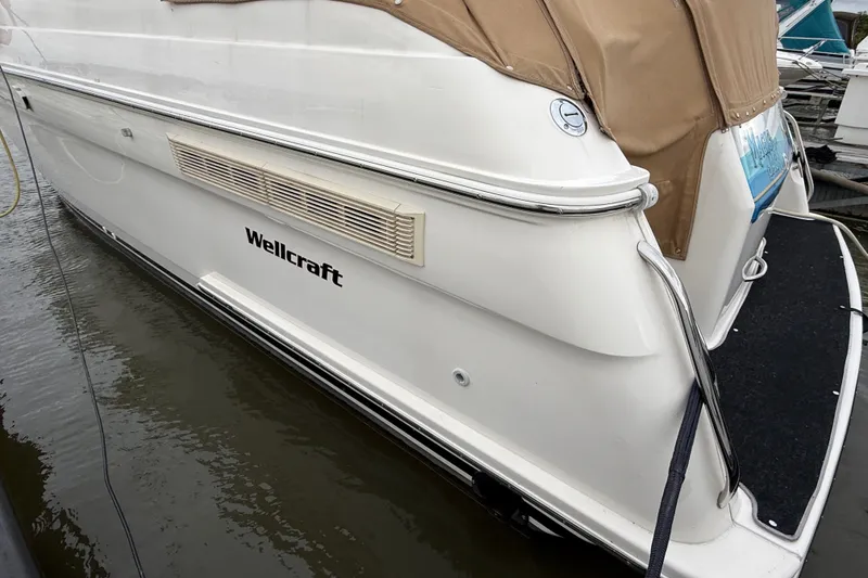 Slide: The Image of 1998 Wellcraft 3200 Martinique boat docked, featuring sleek white hull and tan cover. - 6