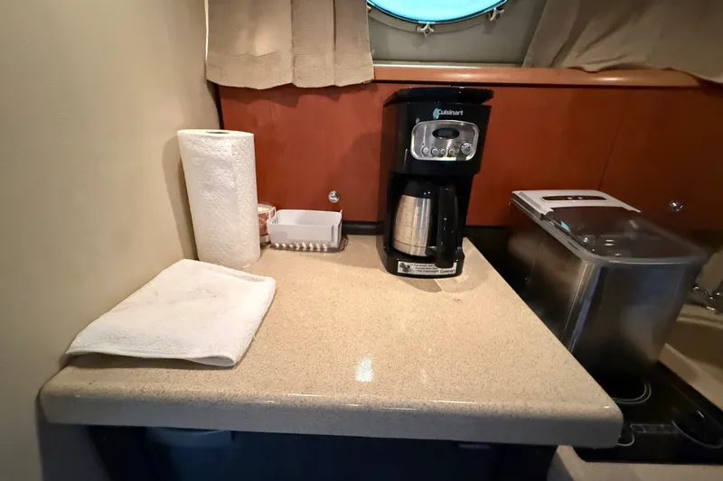 Slide: The Image of Compact kitchen area in a 1998 Wellcraft 3200 Martinique boat with coffee maker and countertop essentials. - 47