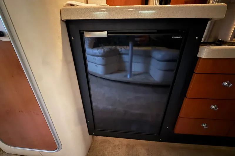 Slide: The Image of 1998 Wellcraft 3200 Martinique interior with compact fridge and wooden cabinetry. - 43