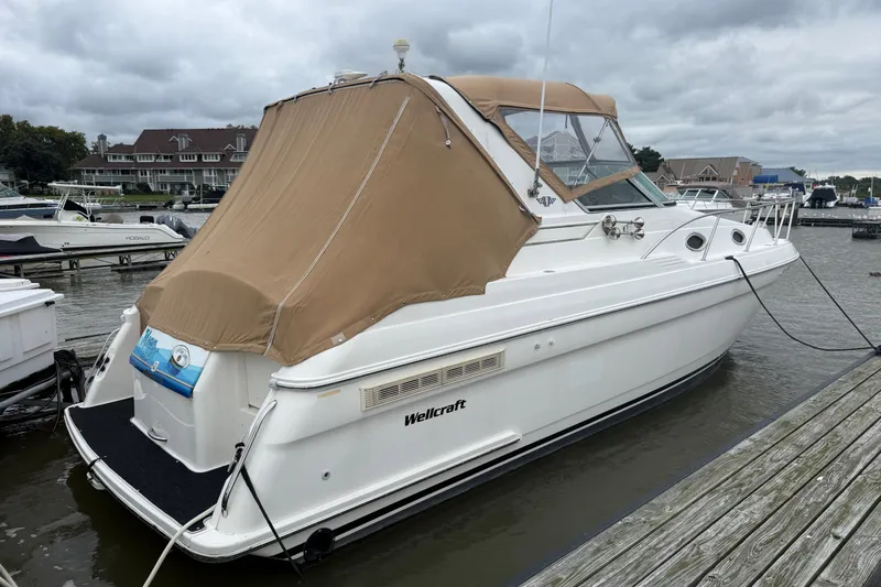 Slide: The Image of 1998 Wellcraft 3200 Martinique boat docked with tan cover, overcast sky. - 2