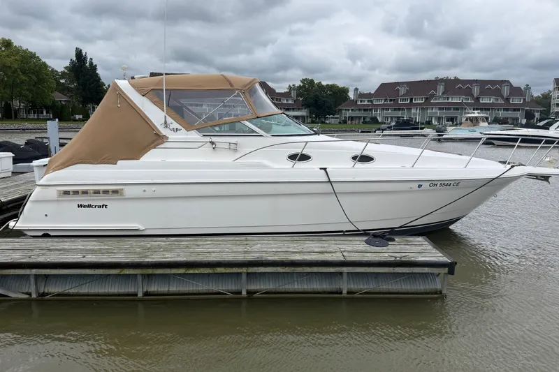 The Image of 1998 Wellcraft 3200 Martinique boat docked at marina, featuring tan canopy and sleek design. - 0