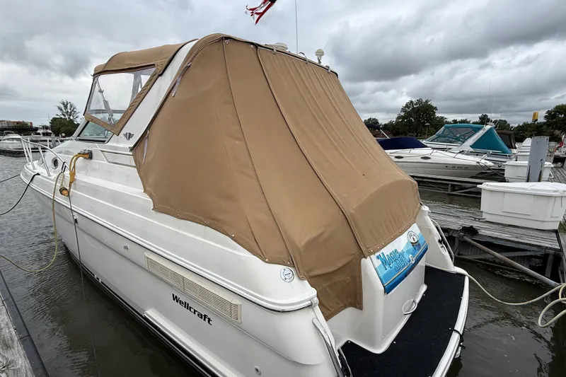 Slide: The Image of 1998 Wellcraft 3200 Martinique boat docked with tan cover, overcast sky. - 5