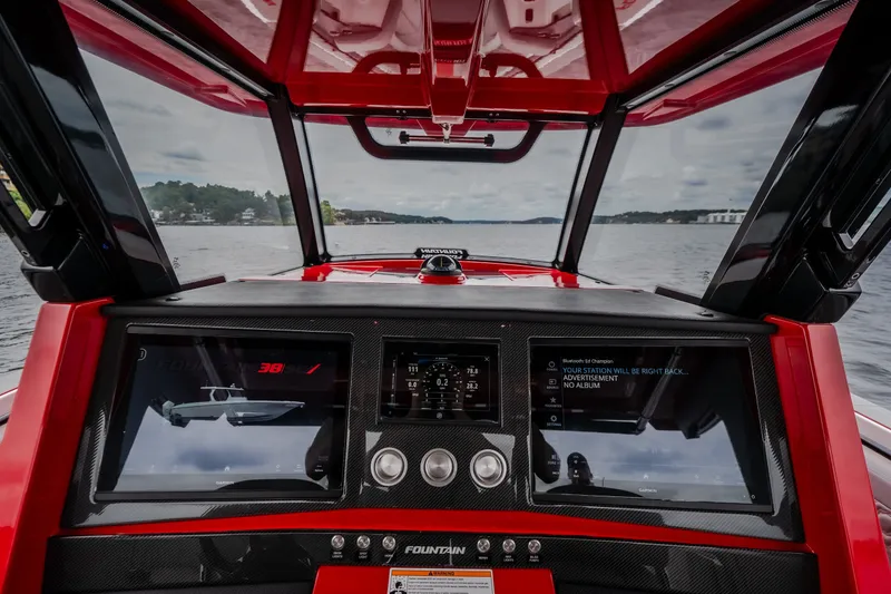 Slide: The Image of Interior view of 2024 Fountain 38 SCX boat dashboard with digital displays on a lake. - 65