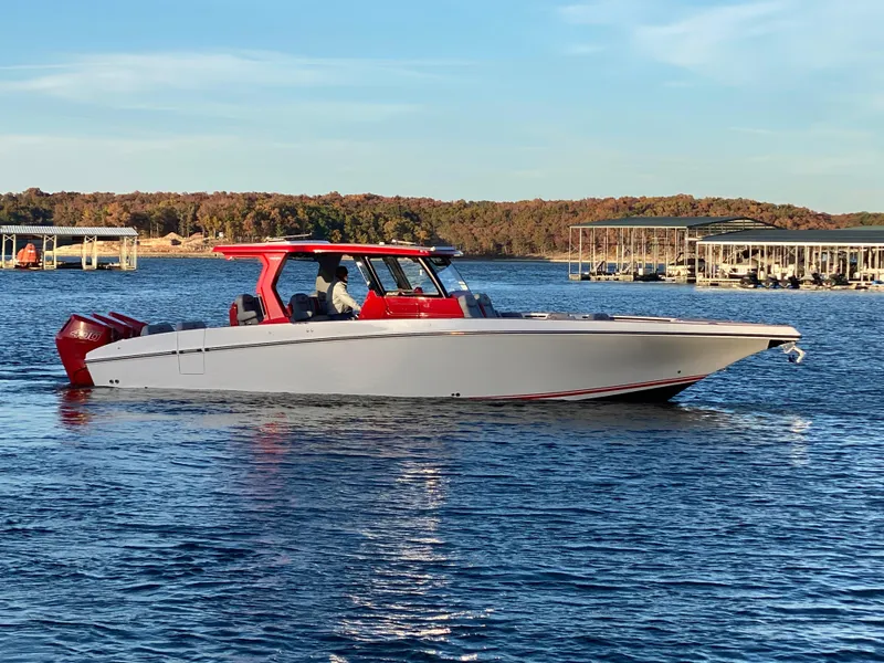 The Image of 2024 Fountain 38 SCX boat on a lake with red accents and clear sky. - 0