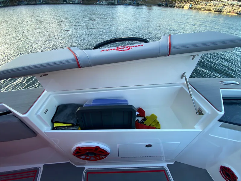 Slide: The Image of 2024 Fountain 38 SCX boat storage compartment with open lid, revealing interior items, dockside view. - 39