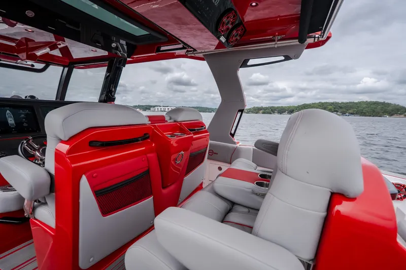 Slide: The Image of 2024 Fountain 38 SCX boat interior with red and gray seating, on a scenic lake. - 31