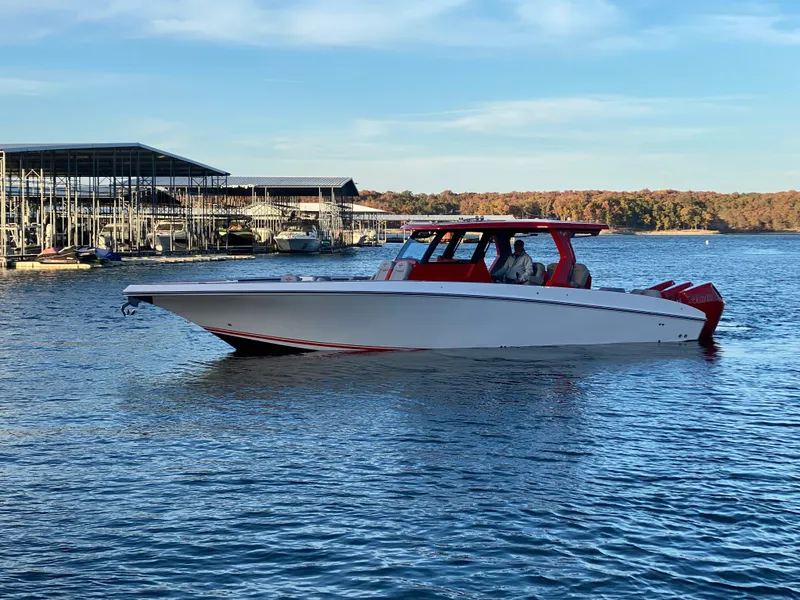 Slide: The Image of 2024 Fountain 38 SCX boat cruising on a serene lake near a marina. - 7