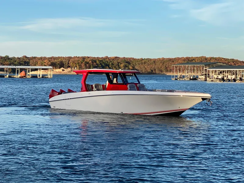 Slide: The Image of 2024 Fountain 38 SCX boat with red accents cruising on a serene lake. - 2