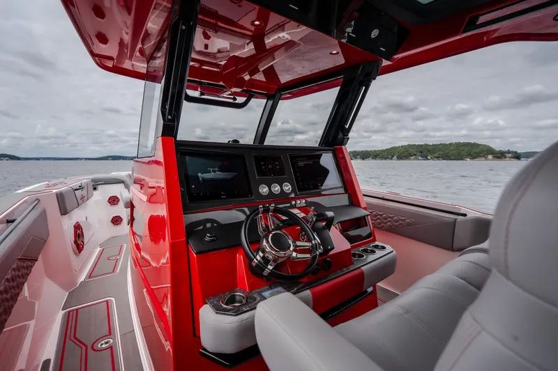 Slide: The Image of 2024 Fountain 38 SCX boat interior with red dashboard and steering wheel on open water. - 49