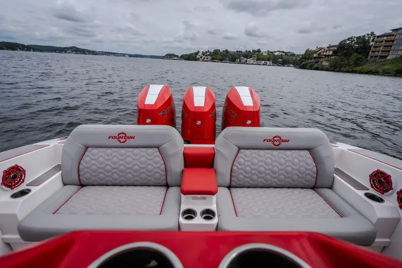 Slide: The Image of 2024 Fountain 38 SCX boat interior with red and gray seating, triple engines, on a lake. - 37