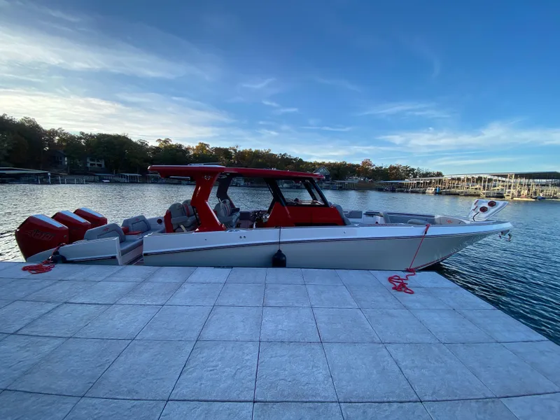 Slide: The Image of 2024 Fountain 38 SCX boat docked by a serene lake under a clear blue sky. - 48