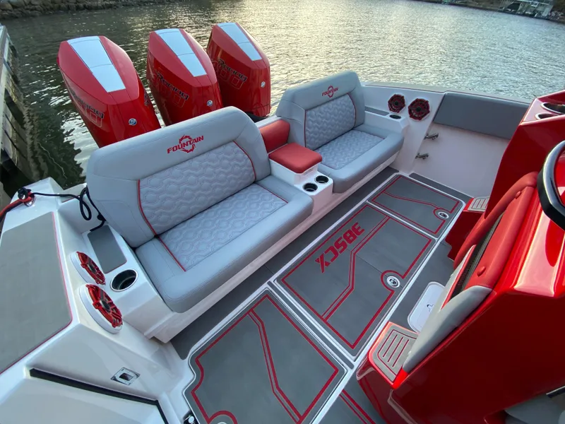 Slide: The Image of 2024 Fountain 38 SCX boat interior with red and gray seating, triple engines, and waterfront view. - 44