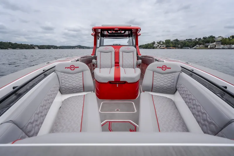 Slide: The Image of 2024 Fountain 38 SCX boat interior with red and gray seating on a lake. - 76