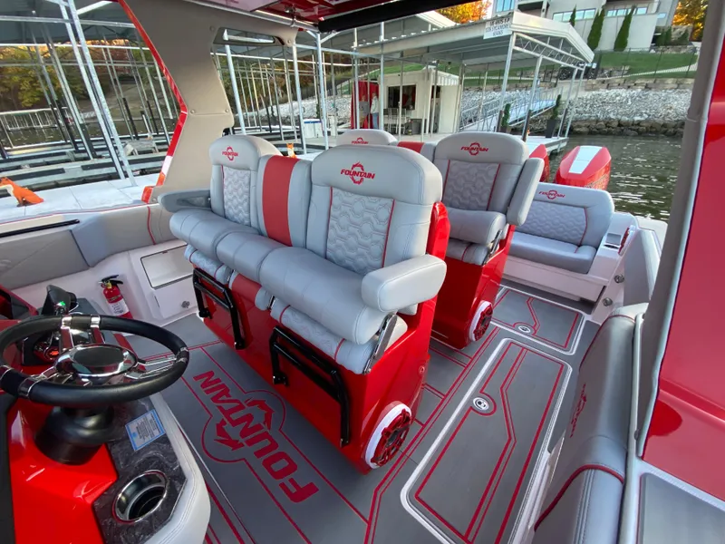 Slide: The Image of 2024 Fountain 38 SCX boat interior with red and gray seating, docked by the water. - 22