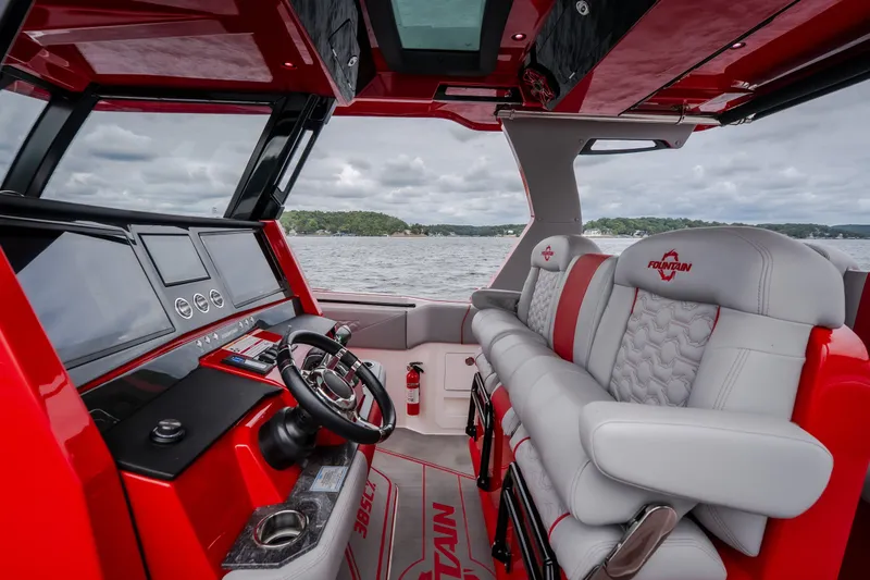 Slide: The Image of 2024 Fountain 38 SCX boat interior with red and gray seating, steering wheel, and dashboard. - 35