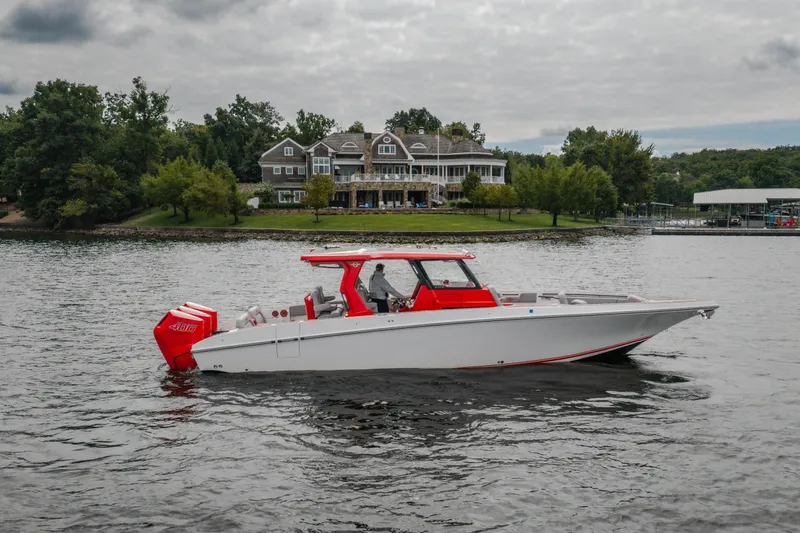 Slide: The Image of 2024 Fountain 38 SCX boat cruising on a lake near a large house. - 7