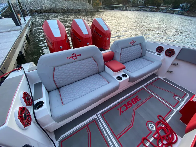 Slide: The Image of 2024 Fountain 38 SCX boat interior with red and gray seating, quad engines, and waterfront view. - 9
