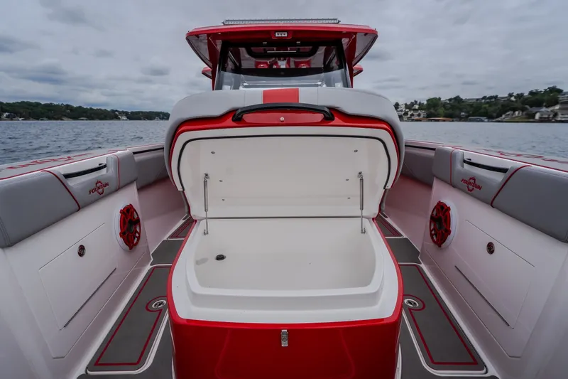 Slide: The Image of 2024 Fountain 38 SCX boat interior with open storage compartment, red and gray seating, and speakers. - 81