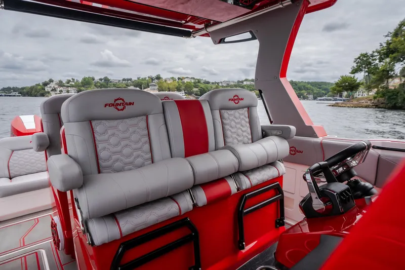 Slide: The Image of 2024 Fountain 38 SCX boat interior with red and gray seating, steering wheel, and lake view. - 55