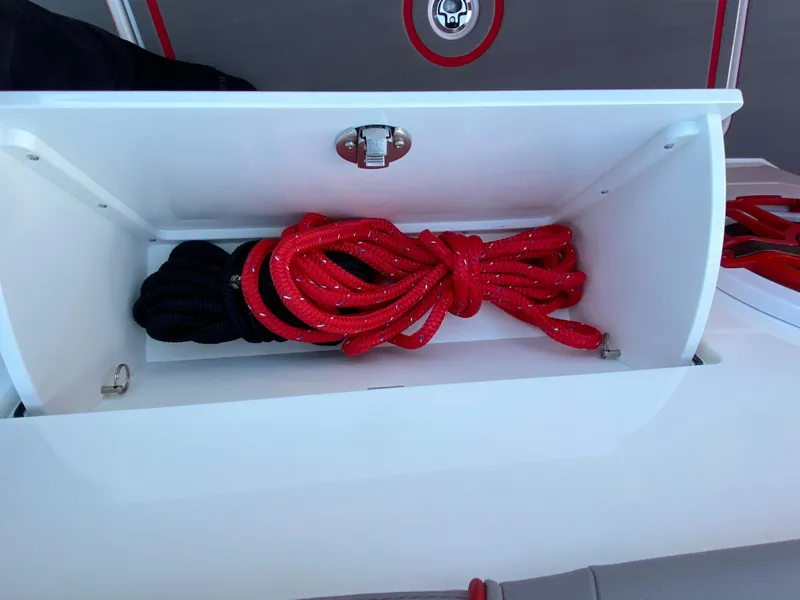 Slide: The Image of Storage compartment with red and black ropes on a 2024 Fountain 38 SCX boat. - 34