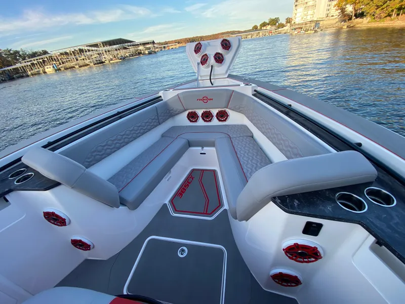 Slide: The Image of 2024 Fountain 38 SCX boat interior with gray seating and red accents on a calm lake. - 30