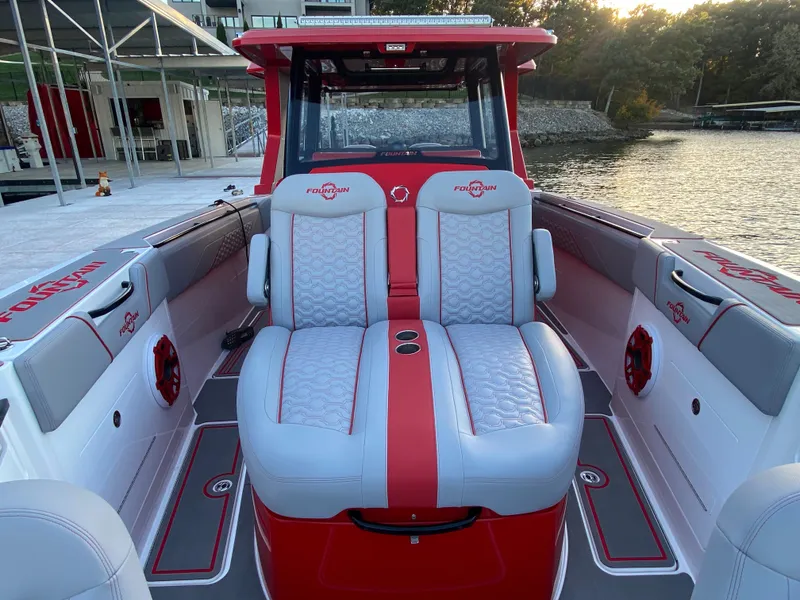 Slide: The Image of 2024 Fountain 38 SCX boat interior with red and gray seating, docked by the water. - 32