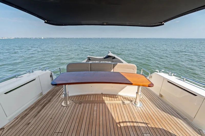 Slide: The Image of 2016 Maritimo M58 yacht deck with wooden table, overlooking serene ocean view. - 8