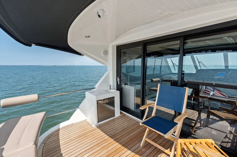 Slide: The Image of 2016 Maritimo M58 yacht deck with seating, ocean view, and sliding glass doors. - 16