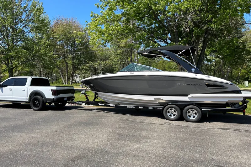 Slide: The Image of White truck towing a 2017 Regal 2800 Bowrider boat on a sunny day. - 1