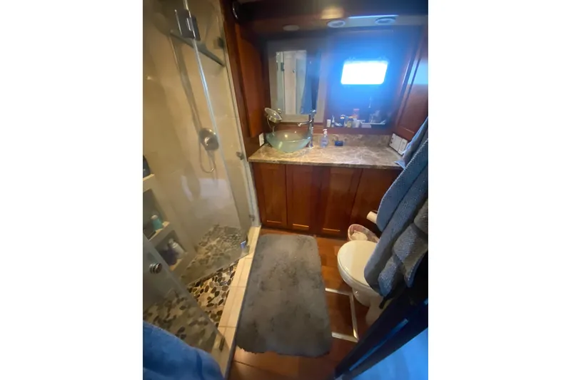 Slide: The Image of Luxurious bathroom in 1990 Hatteras 67 Cockpit Motor Yacht with glass shower and marble countertop. - 12