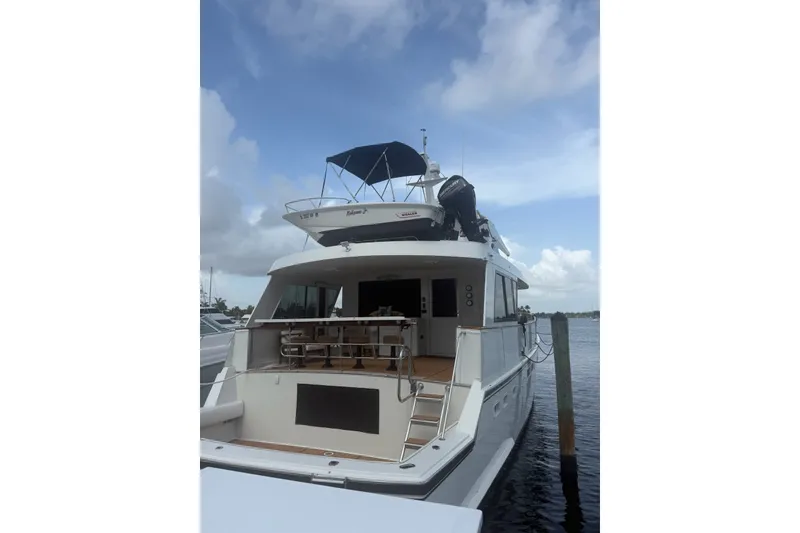 Slide: The Image of 1990 Hatteras 67 Cockpit Motor Yacht docked under a cloudy sky. - 2