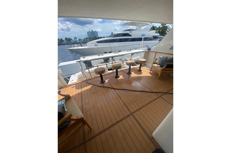 Slide: The Image of 1990 Hatteras 67 Cockpit Motor Yacht deck with seating and scenic marina view. - 5