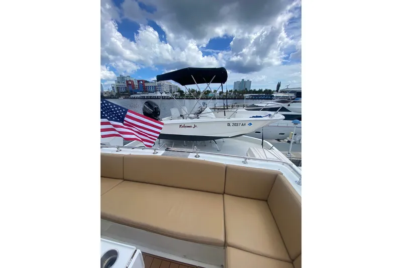Slide: The Image of 1990 Hatteras 67 Cockpit Motor Yacht with American flag, docked under cloudy sky. - 7