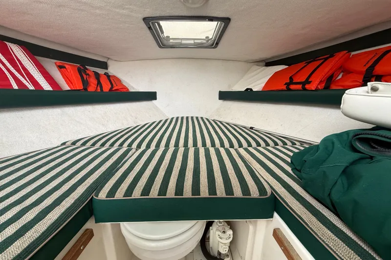 Slide: The Image of Interior cabin of 1999 Pursuit 2460 Denali boat with striped cushions and life jackets. - 24