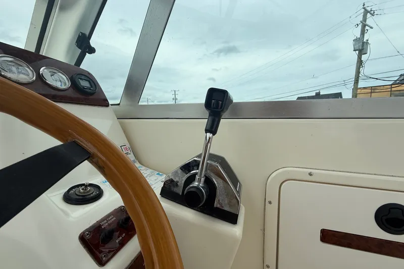 Slide: The Image of 1999 Pursuit 2460 Denali boat dashboard with steering wheel and control lever. - 14