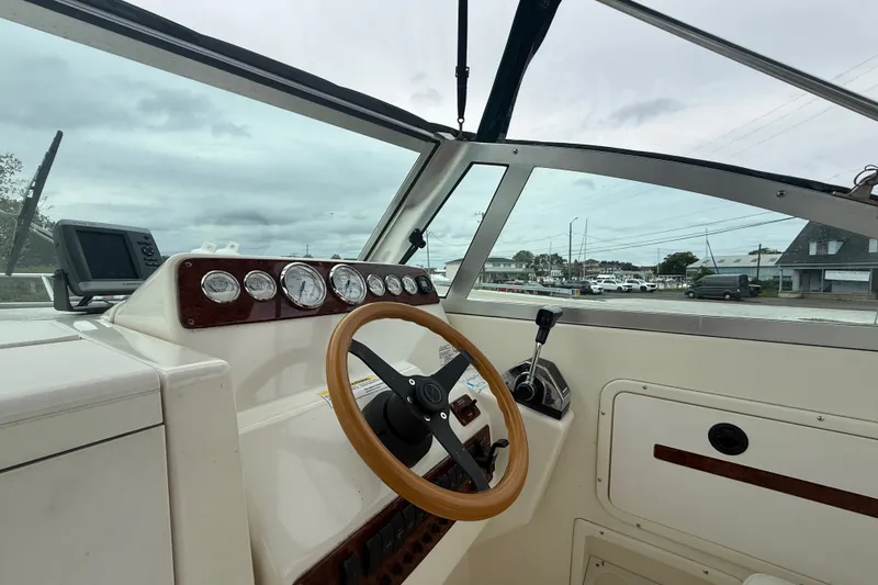 Slide: The Image of Interior view of a 1999 Pursuit 2460 Denali boat cockpit with steering wheel and gauges. - 11