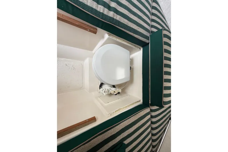 Slide: The Image of Interior view of a 1999 Pursuit 2460 Denali boat, featuring striped seating and storage compartment. - 31
