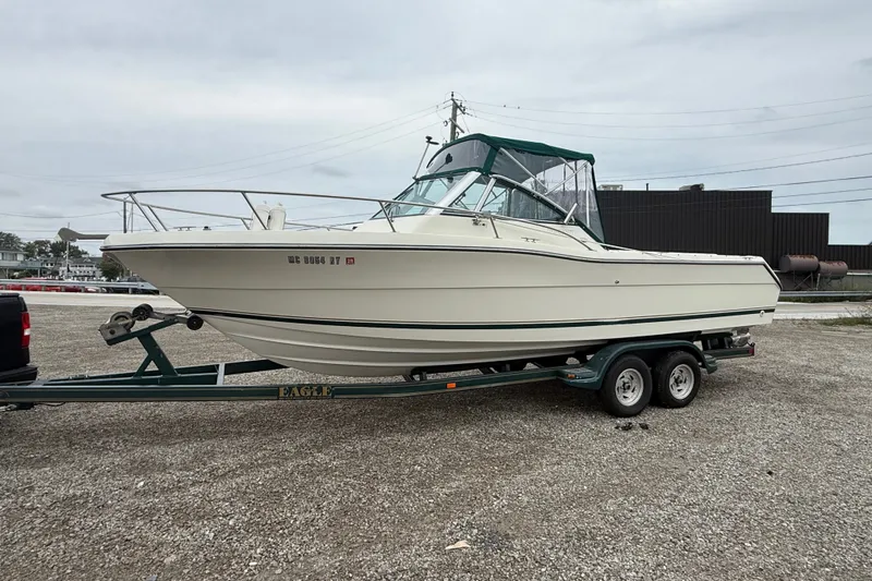 Slide: The Image of 1999 Pursuit 2460 Denali boat on trailer, parked outdoors on gravel. - 4